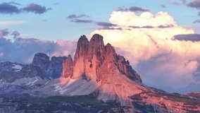 Dramatic sunset alpenglow over Drei Zinnen mountains, with vibrant pink hues illuminating the rugged peaks - Powered by Shutterstock - Get 15% off with code: PIKWIZARD15