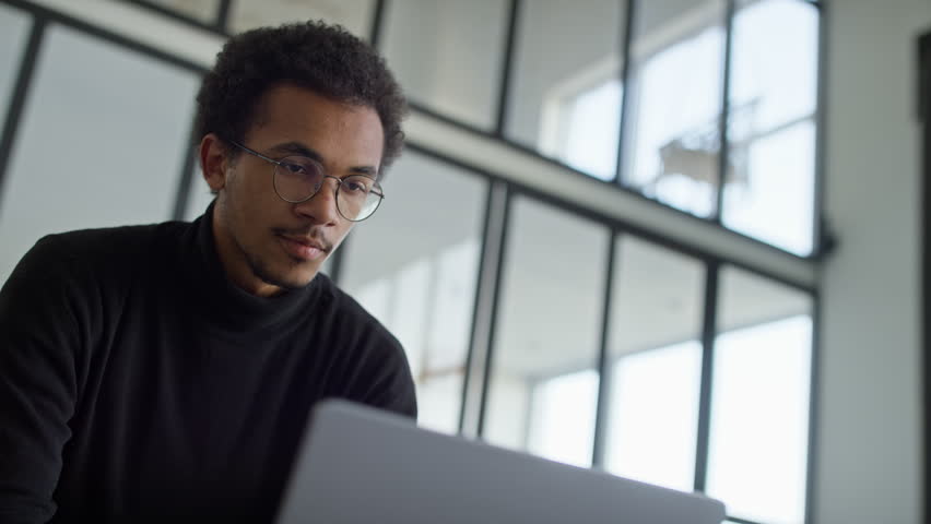 Focused Young Professional Using Laptop in Modern Office