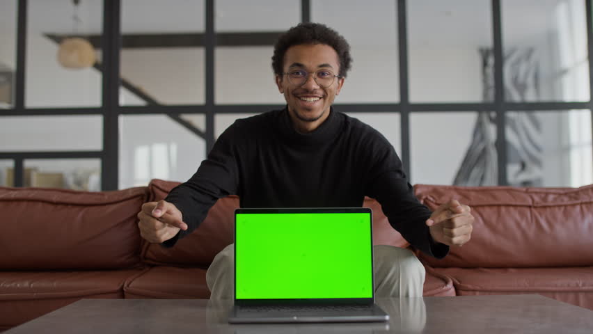 Man Smiling with Laptop Displaying Green Screen in Modern Living Room - Powered by Shutterstock - Get 15% off with code: PIKWIZARD15
