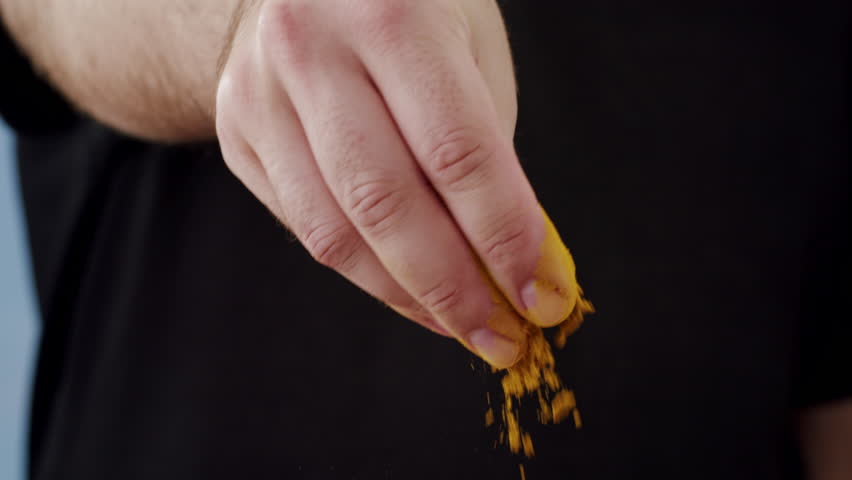 Professional chef adds curry curcuma indian peppers to a pot of boiling food. Restaurant kitchen cooking, colorful spices, dropping spices.