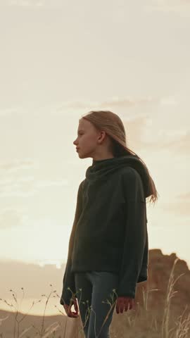 Vertical video a sad schoolgirl stands alone in an empty area, looking away. Themes of loneliness, depression, teenage crisis, family issues, school bullying. A portrayal of a negative, troubled mood