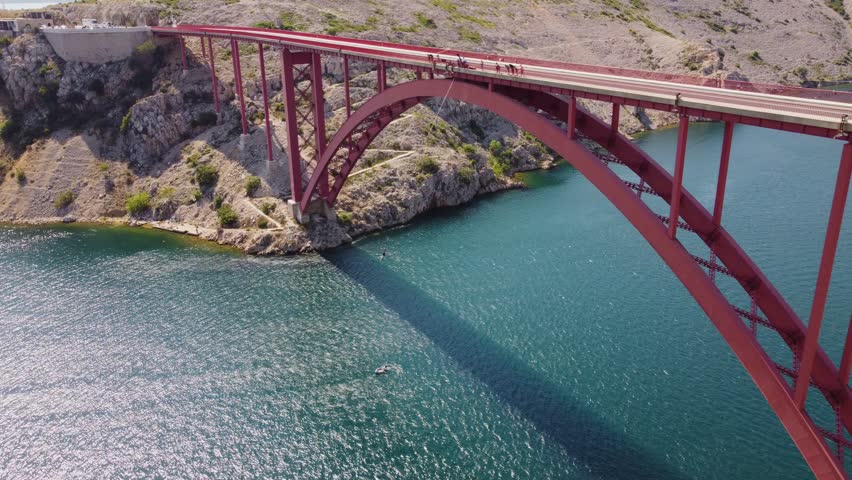 Bungee jumping activity from a bridge above the sea. Aerial view person attached to a rope on the bridge. Maslenica bridge, Croatia, travel destinations.
