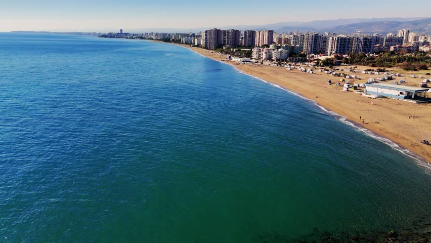 Turquoise water meets golden sand along the coastline of mersin, turkey. Buildings line the shore of this popular vacation destination