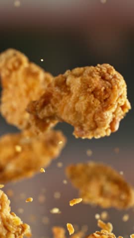 Super Slow Motion of Flying Fried Chicken Wings and Pieces. Abstract Blur Interior on Background. Filmed on High Speed Cinema Camera , 1000fps. Camera in Motion. Vertical Aspect Ratio.