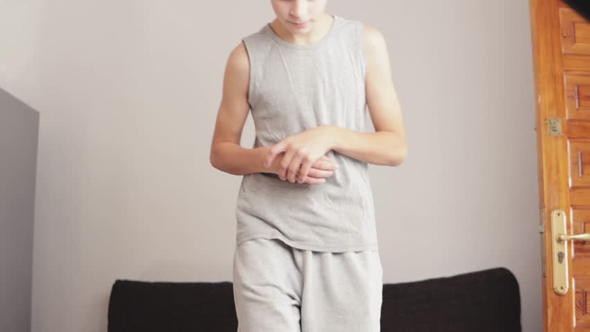 Boy exercising indoors on a mini stepper, focusing on fitness and training. Dumbbells rest on the floor nearby, enhancing the home workout environment