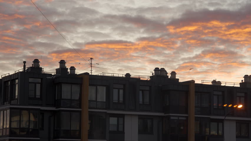 Red clouds lit by the morning sun over an apartment building, dawn in a residential area.