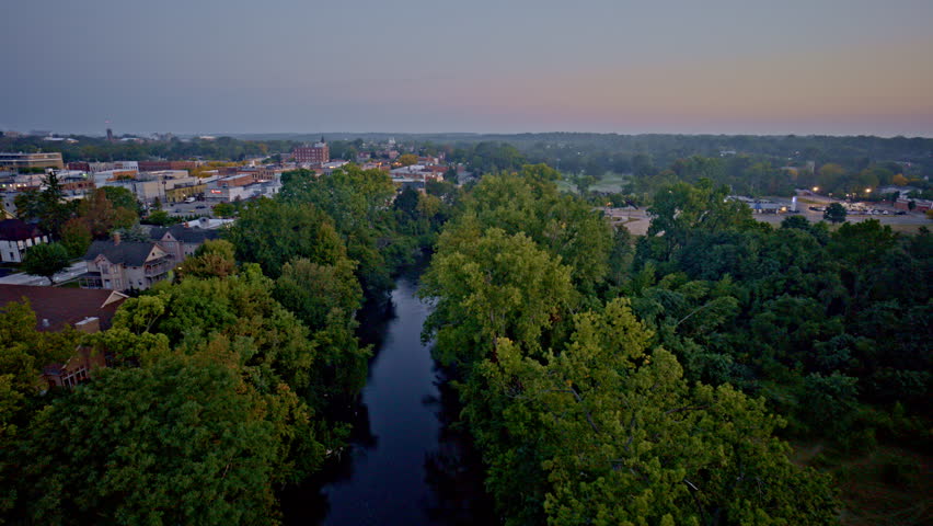 Drone shot flying over river in summer towards Ypsilanti Michigan