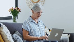 Smiling middle-aged Caucasian woman sit next to couch in living room browsing wireless Internet on computer, happy modern senior female relax on ground at home using laptop pc device, elderly  - Powered by Shutterstock - Get 15% off with code: PIKWIZARD15