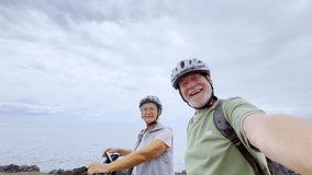 Two happy old mature people enjoying and riding bikes together to be fit and healthy outdoors. Active seniors having fun taking a selfie picture with camera - Powered by Shutterstock - Get 15% off with code: PIKWIZARD15
