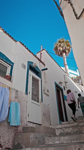 Couple of tourists climbing stairs in a narrow alley of a picturesque town, surrounded by charming architecture and vibrant culture. Tufia, Gran Canaria