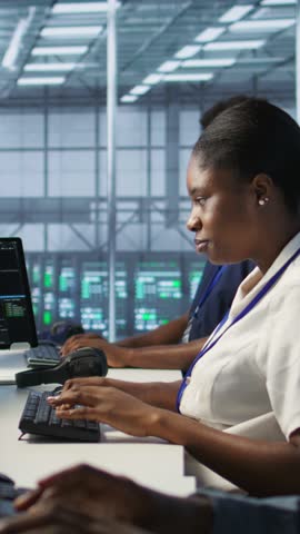 Vertical video Cybersecurity experts in server farm trying to protect equipment from hacker stealing data. Close up of data center IT professionals struggling to delete virus attacking company servers