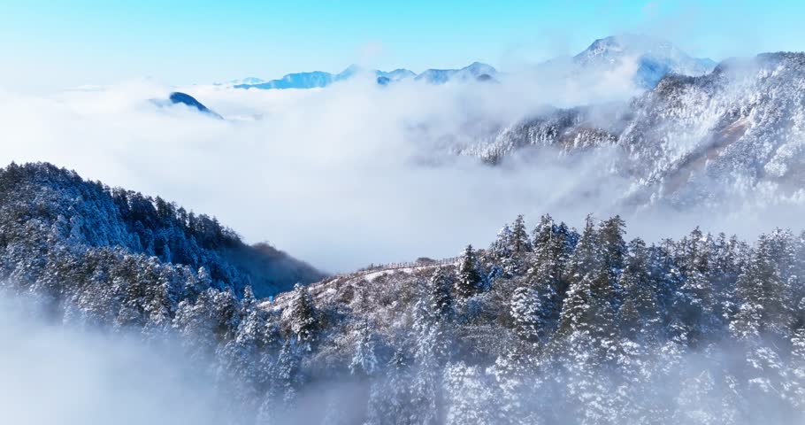 Amazing aerial landscape of winter snowy mountain with mist clouds floating in the sky at Xiling Snow Mountain of Sichuan China