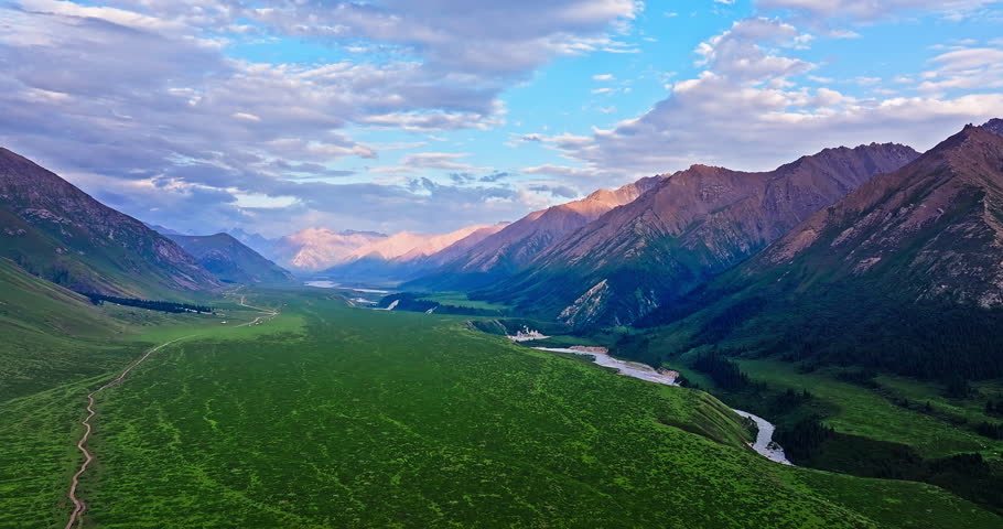 Green grassland and curved river with mountain natural landscape at sunset in Xinjiang. Beautiful scenery along the Duku Highway in China.