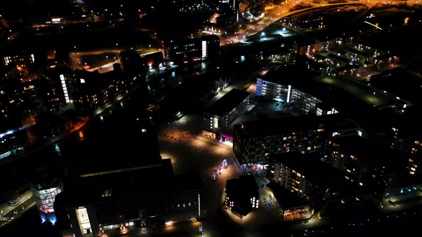 Night time aerial footage of the town of Leeds City Centre taken at night with a drone showing the West Yorkshire city centre all lit up with lights from roads and apartments near the main motorway