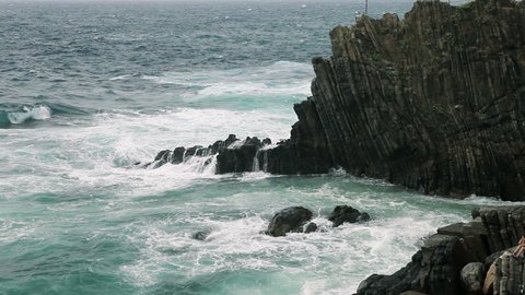 Sea waves splashing through a gap in the rocks.