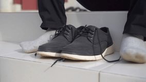 Close up of male hands tying shoelaces at home. Young man in gray pants tying shoelaces of white canvas shoe on granite floor - Powered by Shutterstock - Get 15% off with code: PIKWIZARD15