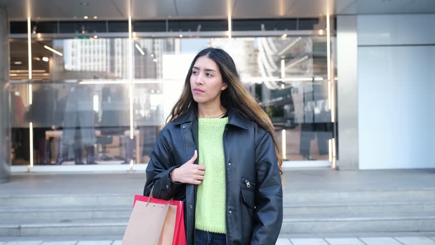 Young adult with shopping bags is standing outside a store
