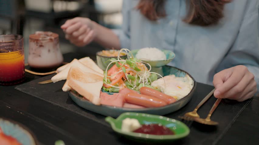 Delicious Breakfast Plate A woman enjoys a hearty and colorful breakfast plate filled with eggs, toast, sausage, vegetables and a refreshing drink.