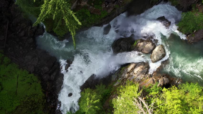 Scenic aerial view above majestic waterfall surrounded by lush green forest.