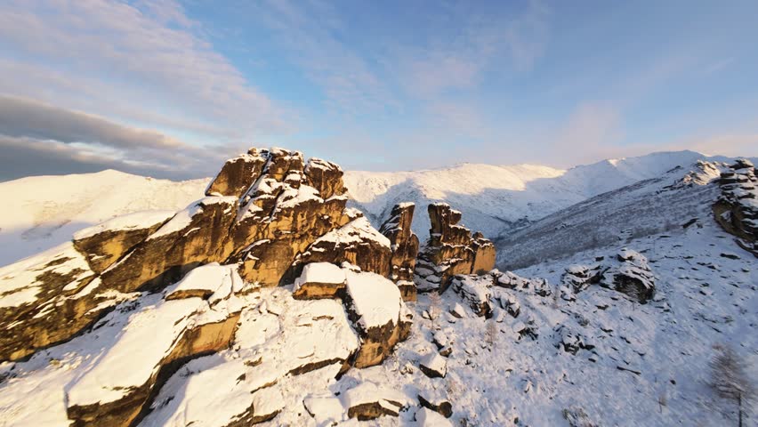 Experience the breathtaking beauty of Yakutia's winter wonderland as a drone glides over snow-covered mountains and rugged terrain, capturing the serene essence of this remote region.