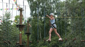A woman in a protective helmet runs an obstacle course along parallel unstable bars in a rope park. - Powered by Shutterstock - Get 15% off with code: PIKWIZARD15