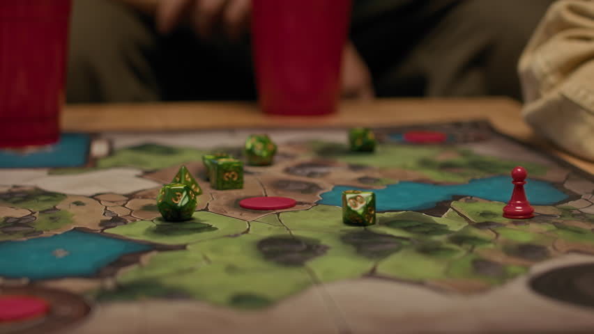 Closeup of strategy board game with map on wooden table beside several plastic cups for friends to play