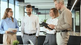 Four business people discussing work together using a tablet in a modern office - Powered by Shutterstock - Get 15% off with code: PIKWIZARD15