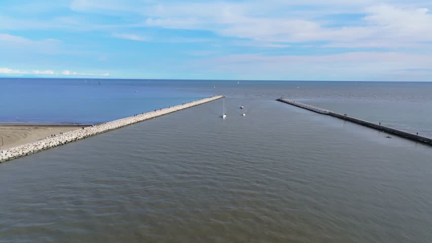 luxury yachts and walkers on the breakwater of Caorle on the Adriatic Sea