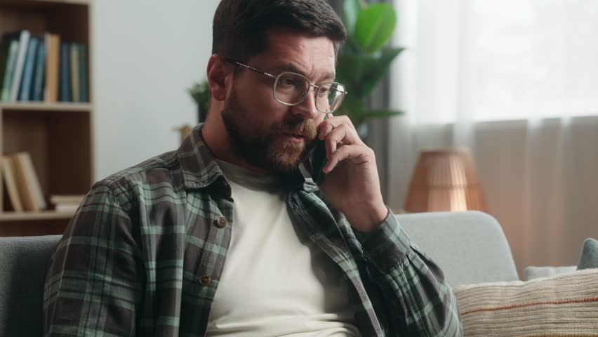 Stressed irritated annoyed angry Caucasian man male guy shopping online problem talking call support help bank service talk argue conflict mobile phone smartphone blocked credit bank card at home