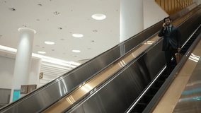 Caucasian project manager using phone calling while using escalator. Skilled caucasian executive manager talking to business team to report and discuss marketing idea or plan. Side view. Exultant. - Powered by Shutterstock - Get 15% off with code: PIKWIZARD15