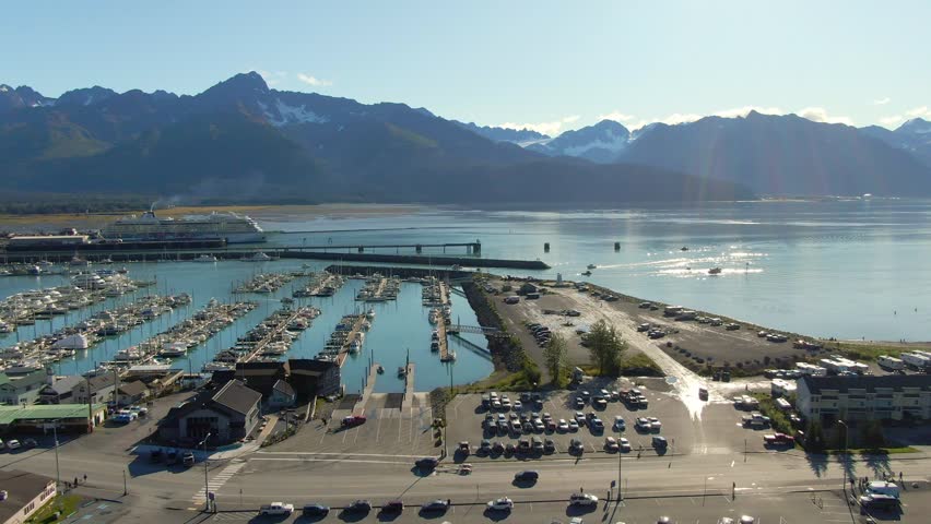 Sunny aerial view of Seward, Alaska, during the fall season, with Seward Bay visible and a huge cruise ship parked in the bay. Ideal for travel, scenic, and seasonal content