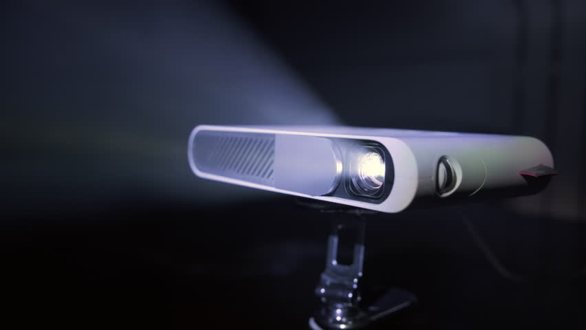 Modern pocket video projector showing film emitting beam of light.