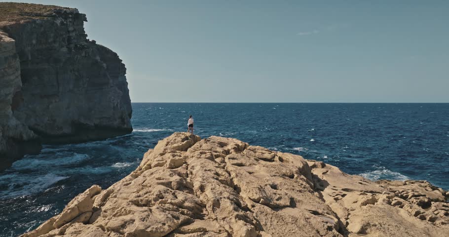 Woman Walking on Rocky Terrain by Fungus Rock in Malta with Stunning Aerial Views of Mediterranean Sea and Coastline. High quality 4k footage