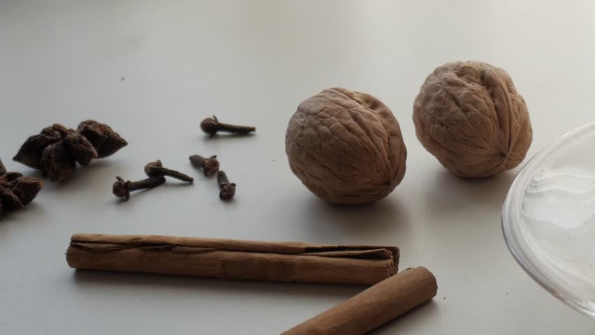 Spices and walnuts arranged on a table beside a glass of coffee, suggesting cozy autumn flavors