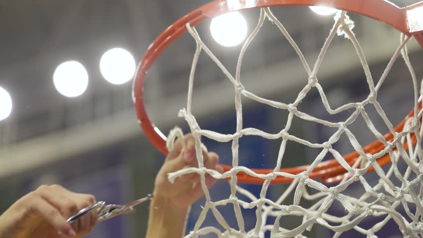 A closeup of a basketball player cutting down the nets after winning the championship.