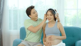 Beautiful pregnant wife with headphones enjoys listening to music for relaxation while husband take care of her, Mom and Dad feeling happy smiling peaceful while take care baby in the womb  - Powered by Shutterstock - Get 15% off with code: PIKWIZARD15
