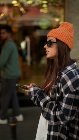 Urban Style A Young Woman Dressed in a Beanie and Flannel, Texting on Her Smartphone