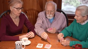 Three family members play cards at a wooden table in a warm, inviting cabin, showcasing togetherness and fun during their quality time together. - Powered by Shutterstock - Get 15% off with code: PIKWIZARD15