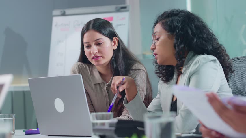 Young corporate office female colleagues or coworkers brainstorming, discussing and working together on an office project or assignment to solve business queries in modern a start up workplace meeting