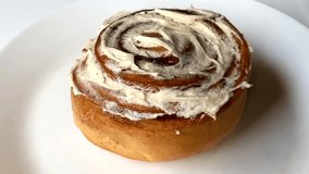 Delicious cinnamon roll with creamy icing on a white plate background. - Powered by Shutterstock - Get 15% off with code: PIKWIZARD15