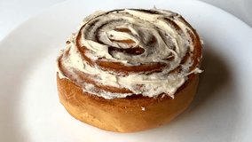 Delicious cinnamon roll with creamy icing on a white plate background. - Powered by Shutterstock - Get 15% off with code: PIKWIZARD15