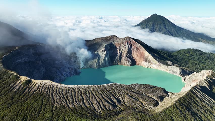 Aerial view Drone shot of fog at Kawah Ijen volcano with turquoise sulfur water lake and sunrise light.Amazing nature landscape view at East Java,Indonesia.Beautiful light Natural landscape background