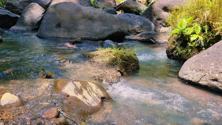 The river water flows over small, large rocks which are very beautiful