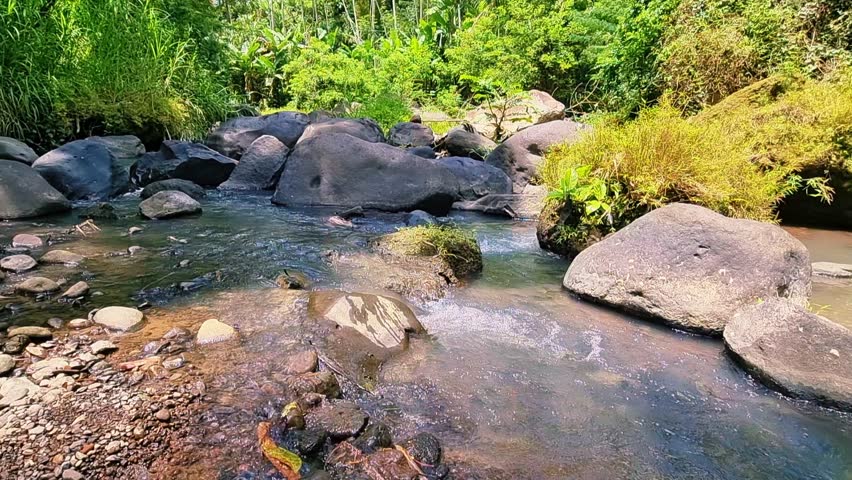 Mountain river water flows coolly between large rocks