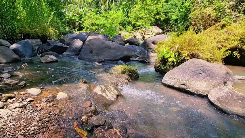 Mountain river water flows coolly between large rocks