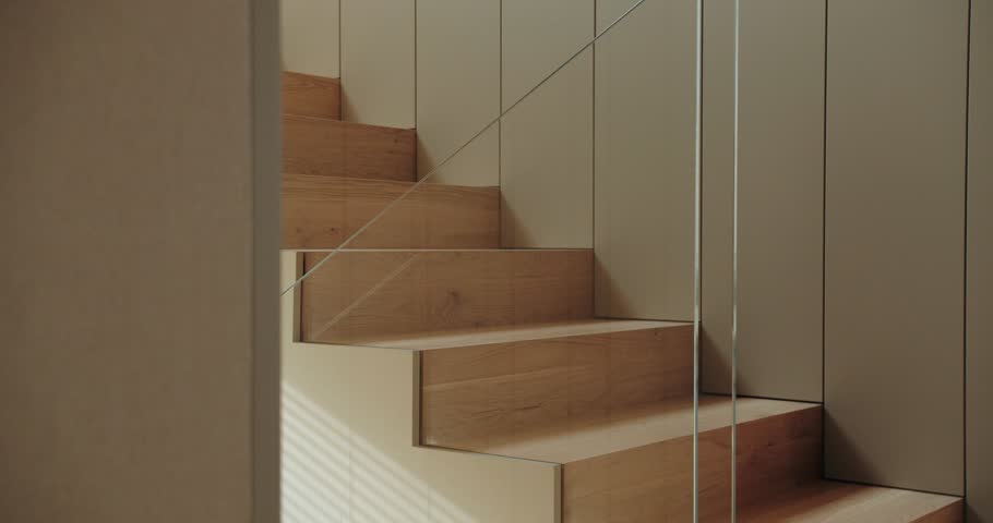Elegant wooden stairs ascend between minimalistic walls, highlighted by natural sunlight, creating a contemporary living space atmosphere. Modern Interior Design Featuring Elegant Wooden Staircase