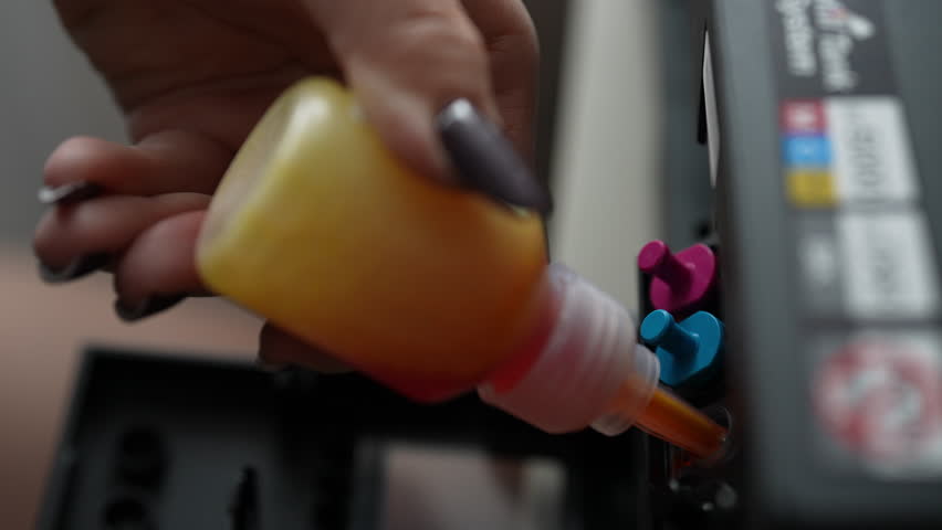Close-up of woman hands carefully refilling yellow ink cartridge for home printer, demonstrating cost-effective and sustainable approach to printing. Technician filling printer cartridge with ink.