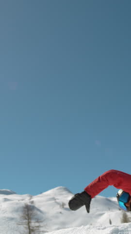 SLOW MOTION WARP, LENS FLARE, CLOSE UP Young pro snowboarder jumps off kicker and does a spinning trick. Spectacular shot of winter athlete riding his snowboard and doing a grab high in the sunny sky