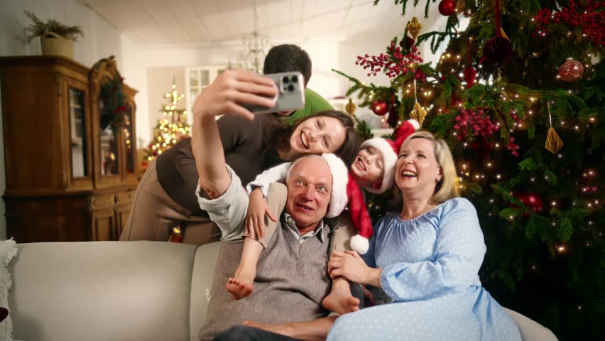 Funny parents, child and grandparents taking family photo by smartphone in Xmas. Celebrating Christmas together, happy people of three generations smiling and laughing, traditional family holiday