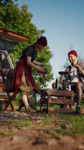 People traveling by campervan and cooking food on gas torch, vertical video. Happiness and freedom when using motorhome for weekend trip and tourism, independent tourists enjoying tasty meal in nature